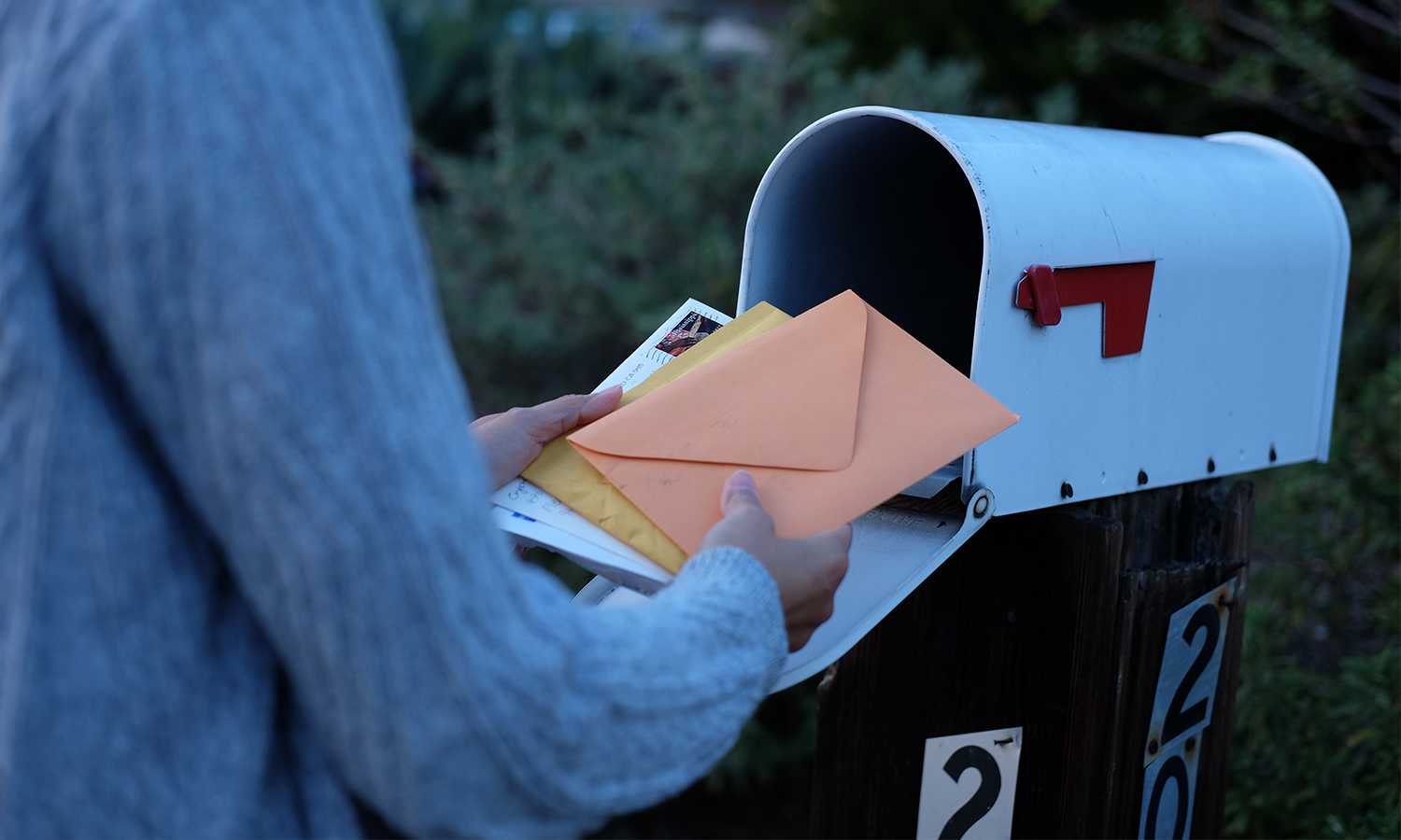 A person takes mail out of a residential mailbox.