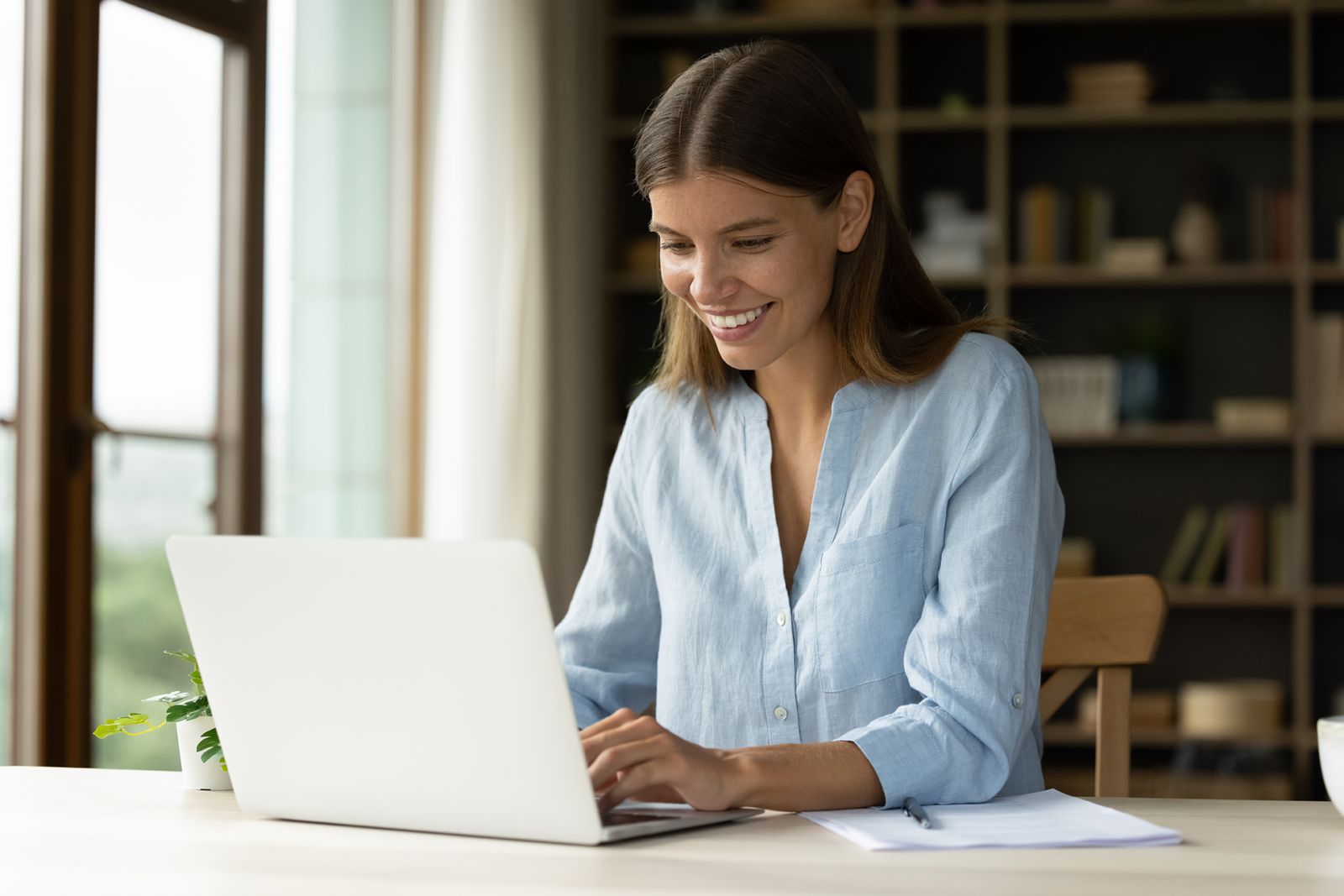 A smiling woman uses a laptop.