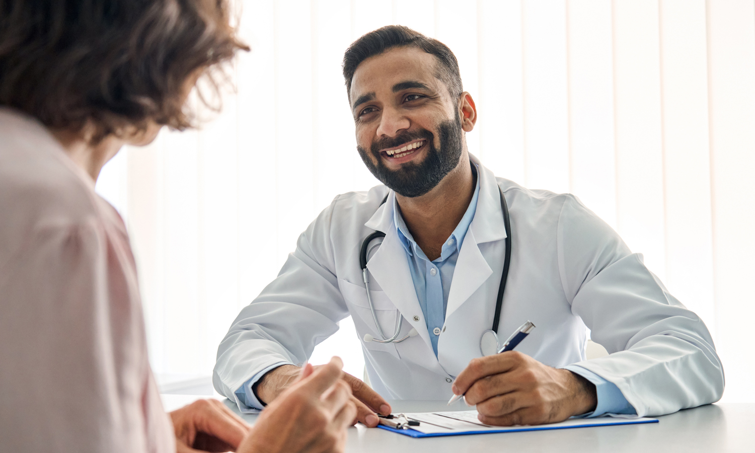 A smiling doctor speaks with a patient in an office.