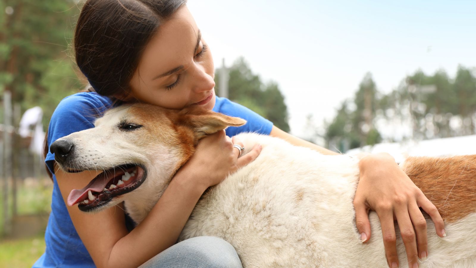 A woman lovingly hugs a dog.